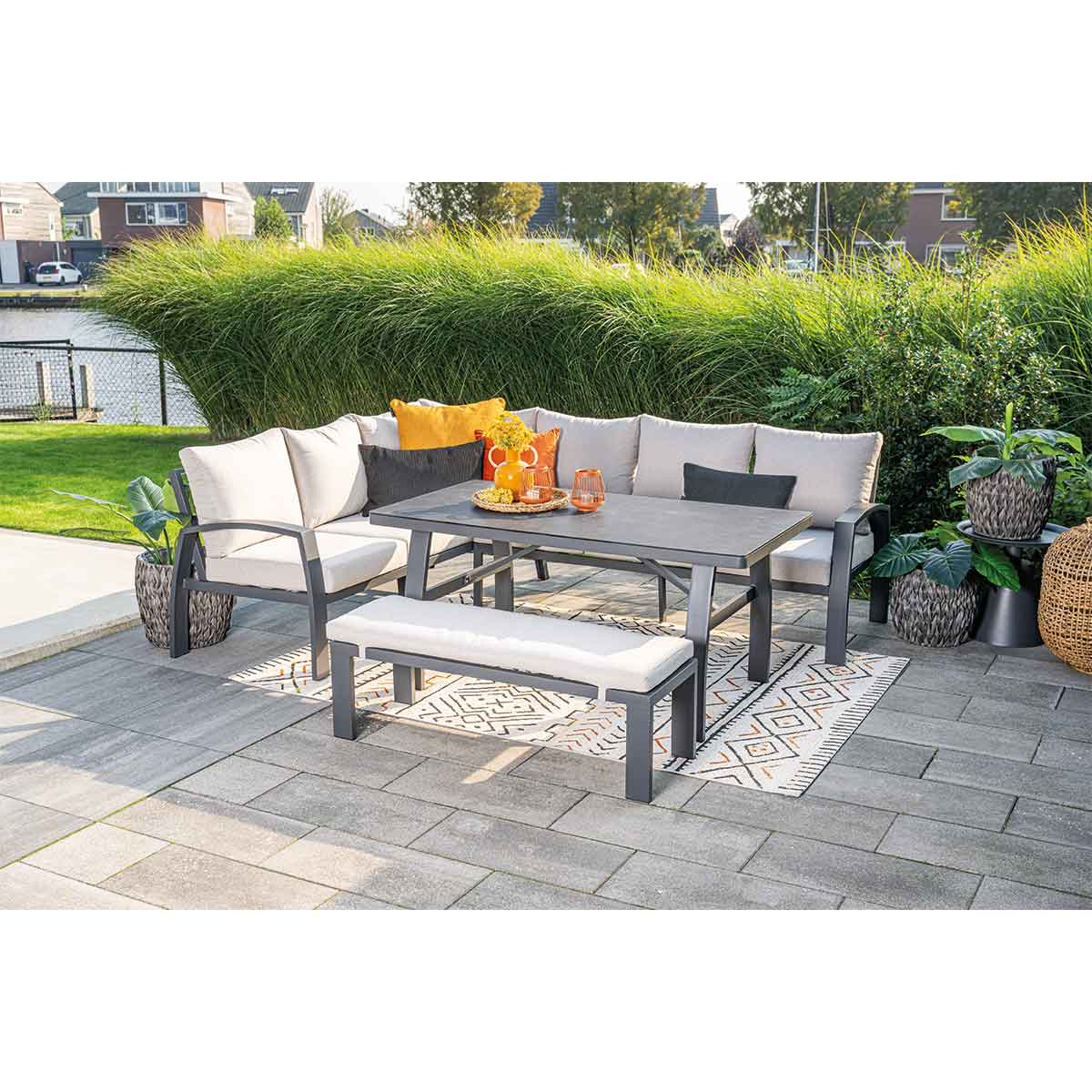 Patio set met hoekbank, bank en tafel. Grijze kussens, zwarte tafel en kleed.
