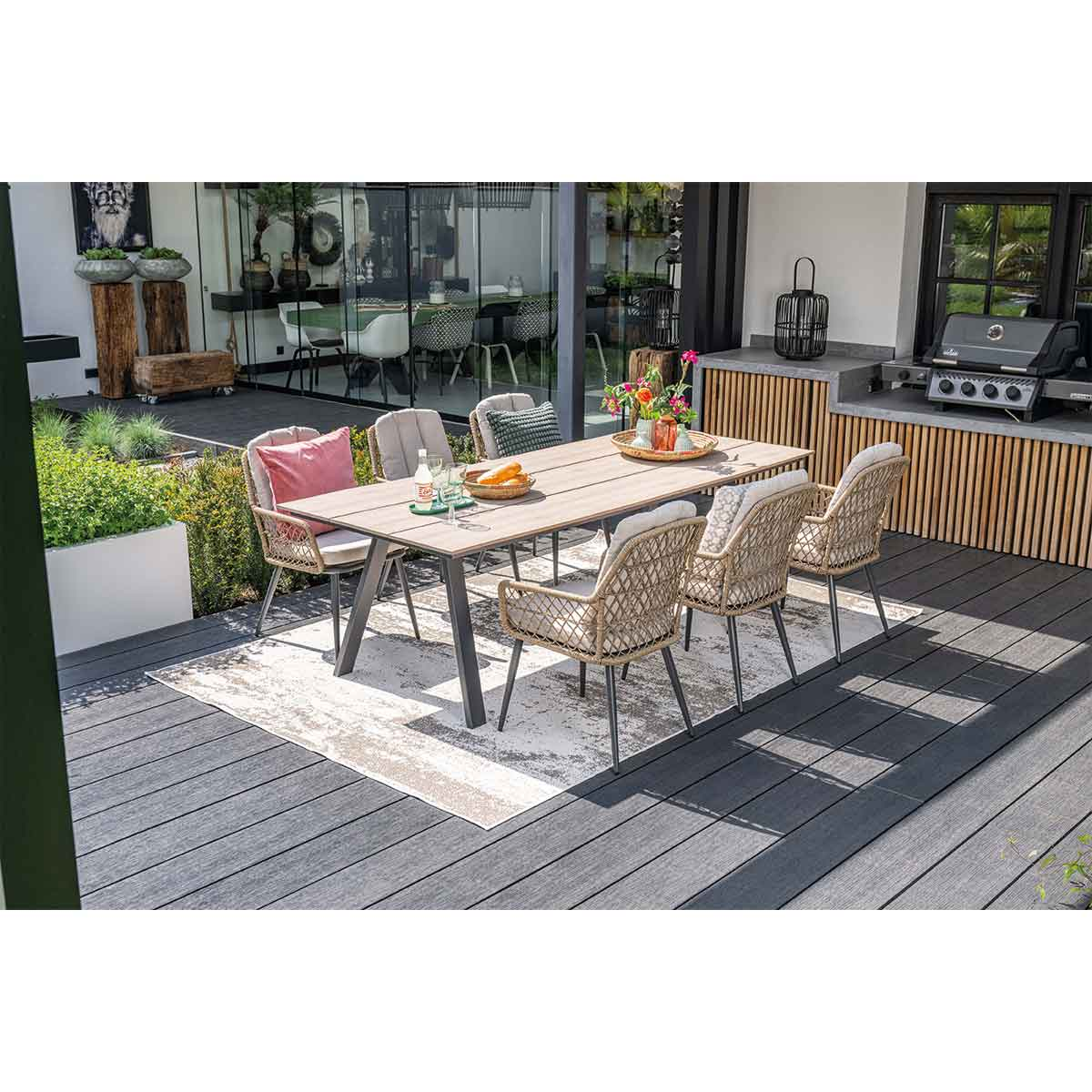 Un ensemble de salle à manger extérieur. Une table avec des chaises, un tapis et un grill sont dans la scène.