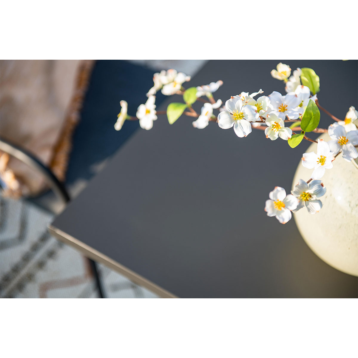 Close-up of flowers on a table. A light colored vase is on the table.
