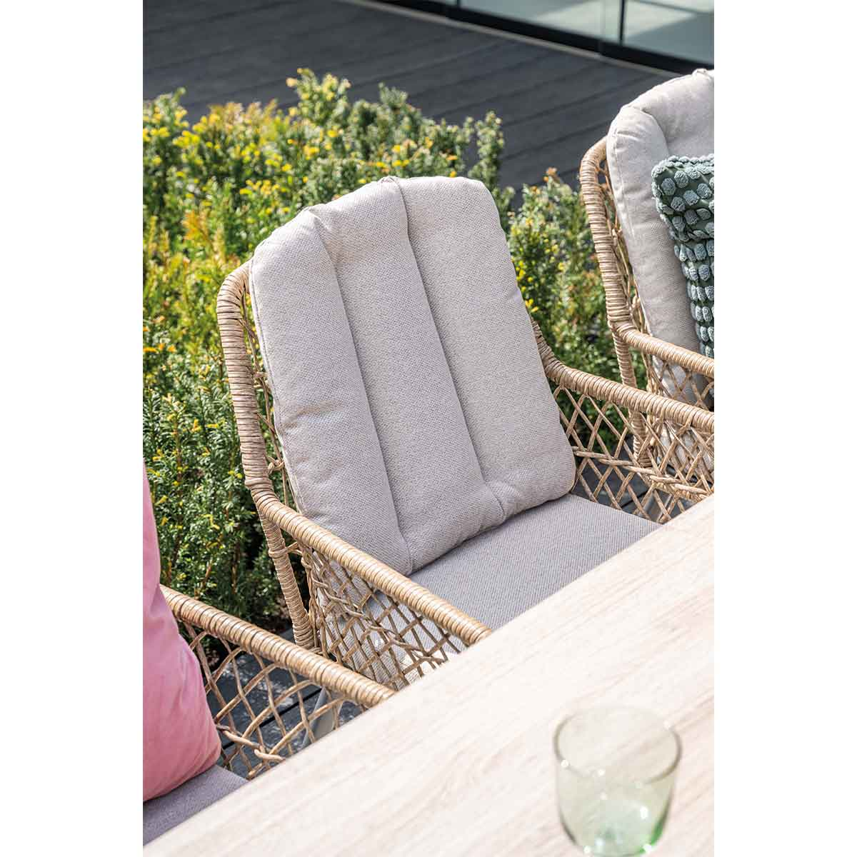 Deux chaises en osier avec coussins. Plantes vertes en arrière-plan. Table en bois.