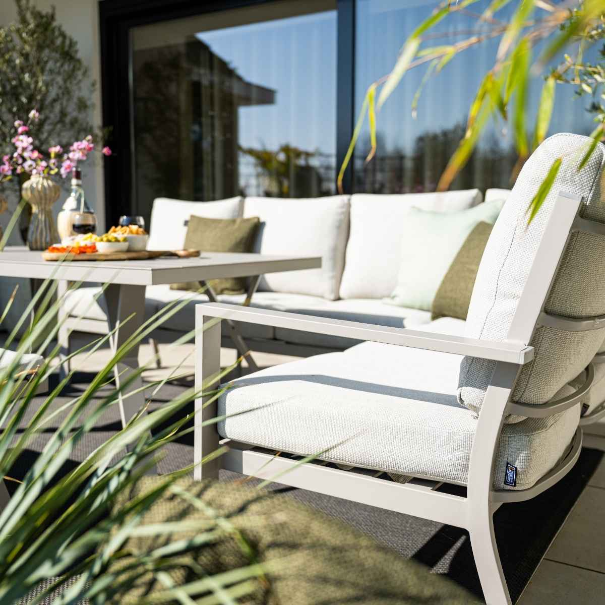 Aménagement de patio extérieur avec nourriture et boissons sur la table, un canapé et des plantes.