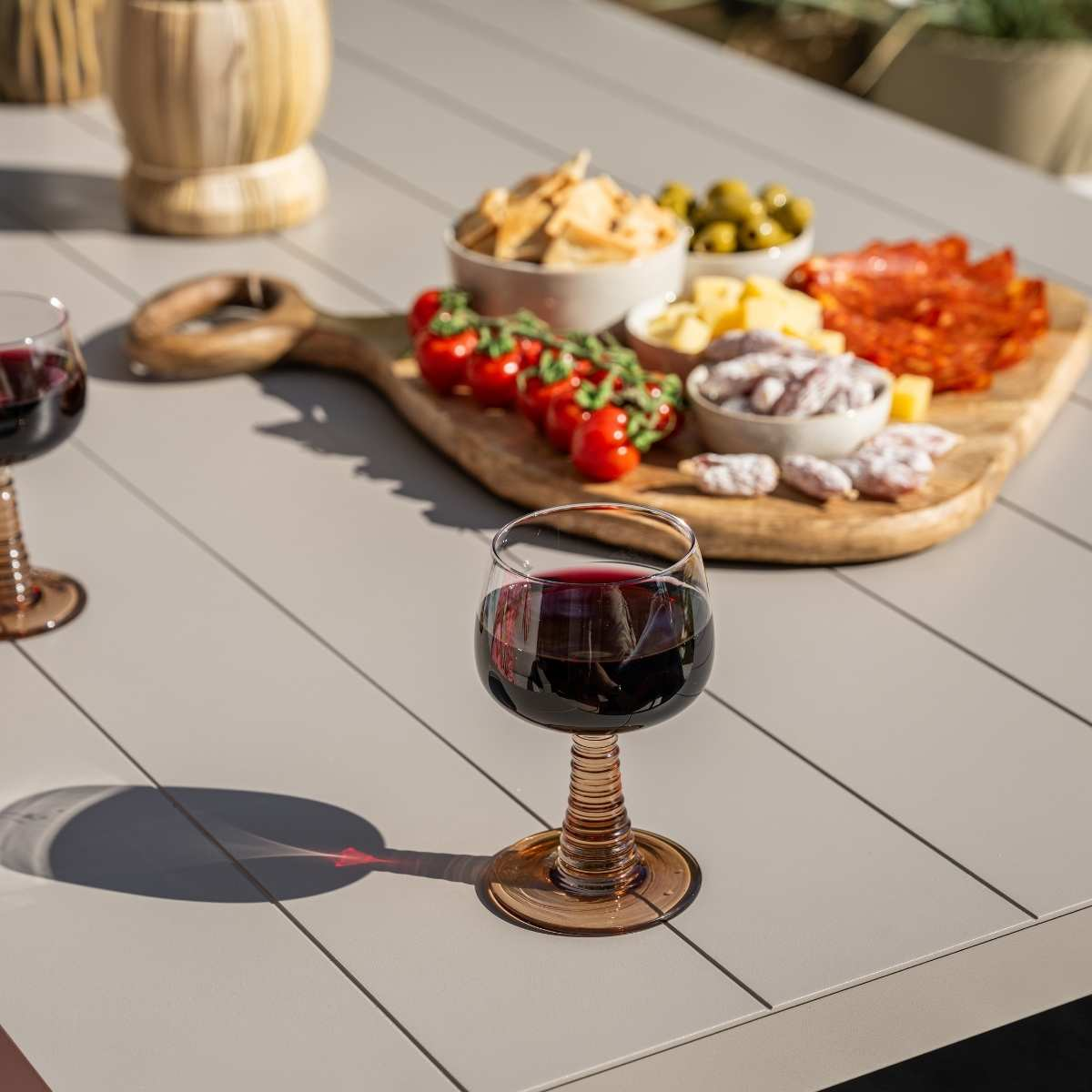 Une table avec nourriture et boissons. Verres à vin, planche de charcuterie avec olives et viandes. Table grise.