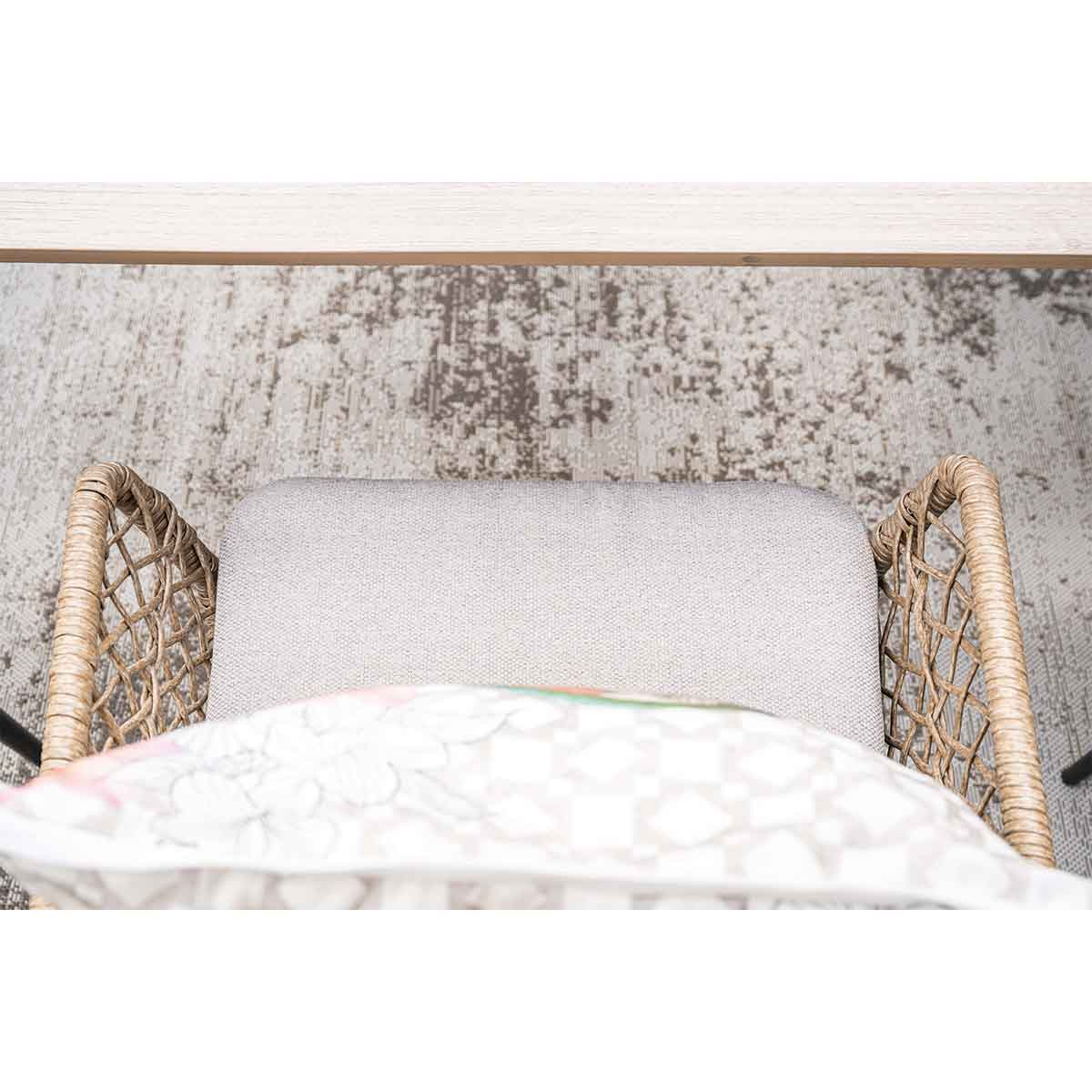 Top view of a wicker chair with a gray cushion and a patterned pillow.