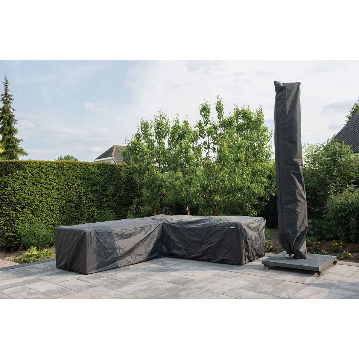 Patio set covered with dark grey covers, umbrella cover, and green hedge.