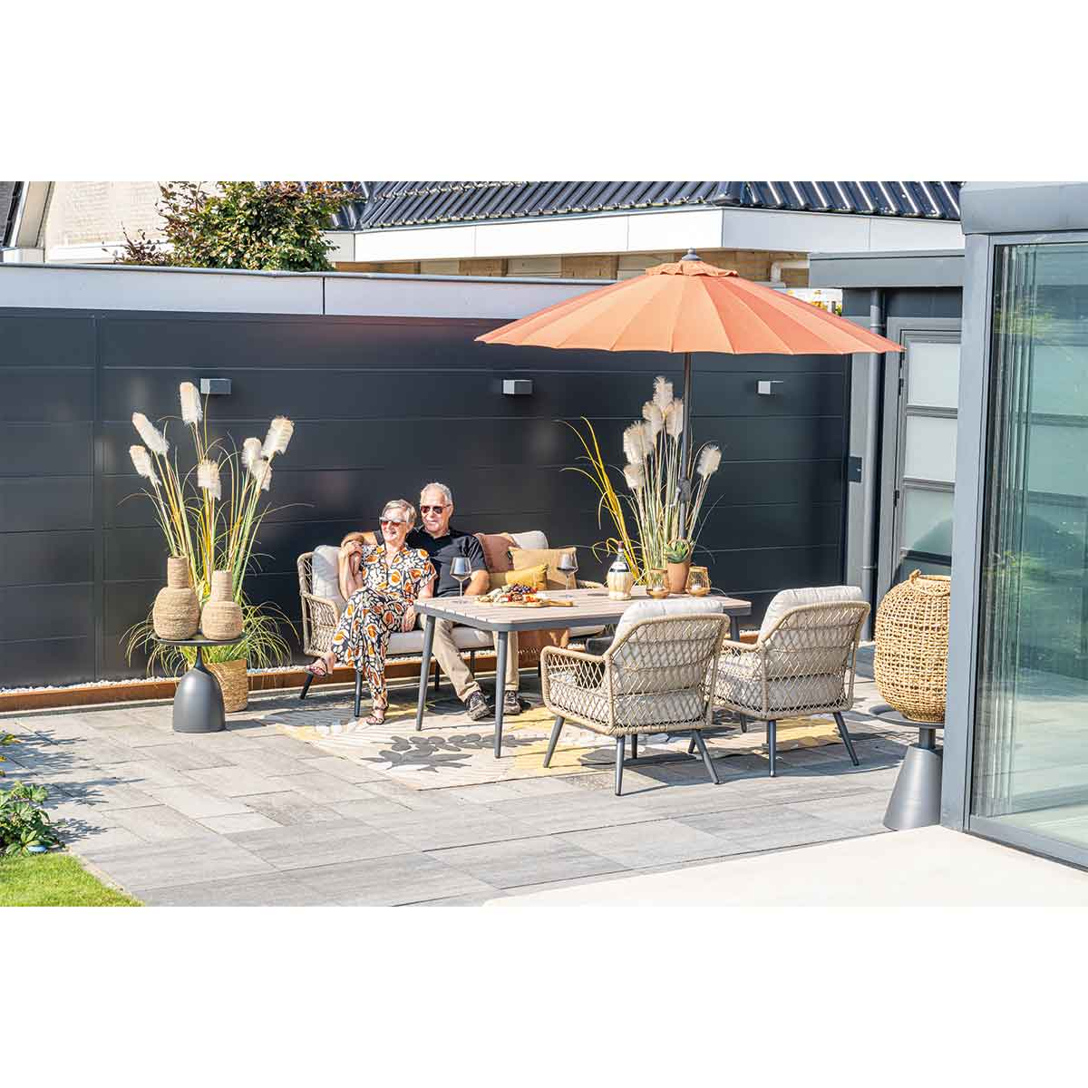 Un couple assis à une table avec un parasol orange et des meubles de jardin.