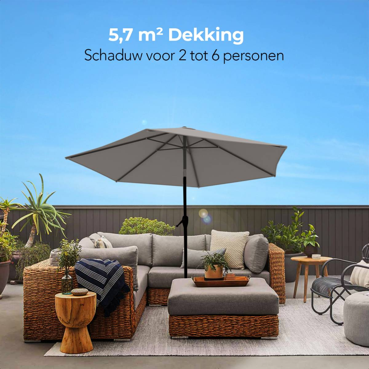 Een grijze parasol op een terras, met tuinmeubels en een blauwe lucht.