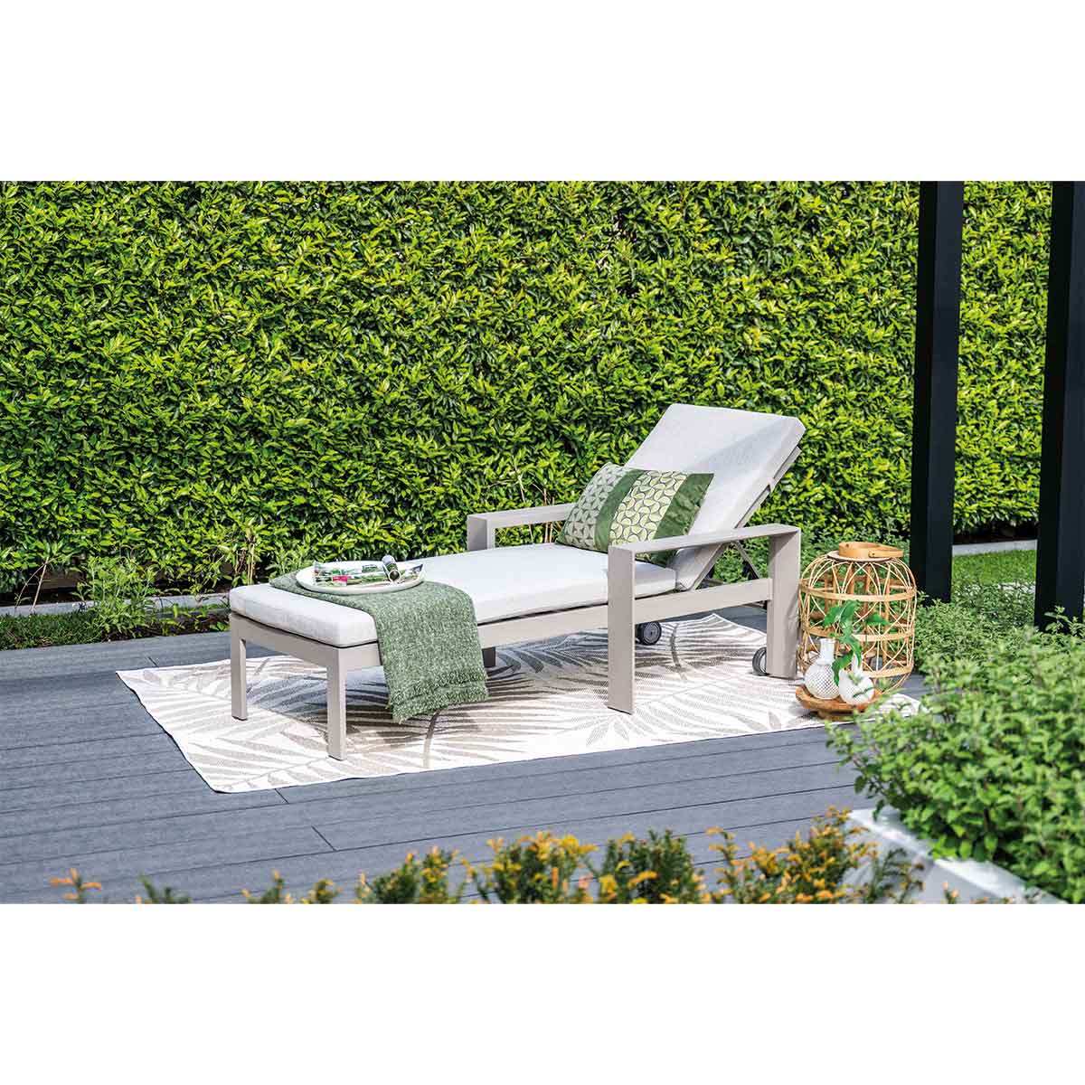 Outdoor lounge chair with cushion, pillow, and blanket, set on a deck.