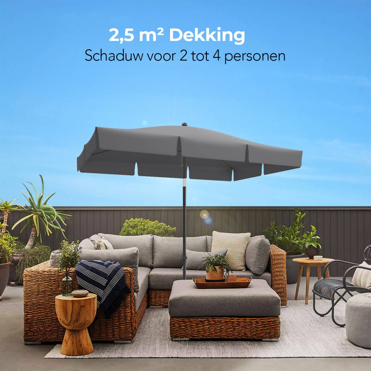 Een grijze parasol biedt schaduw boven een loungeset met een blauwe lucht.