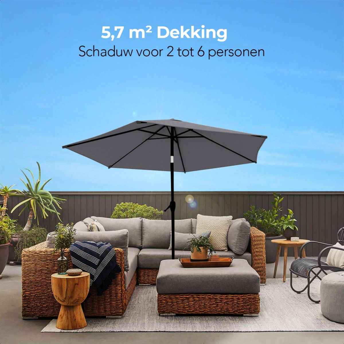 Grijze parasol boven grijze loungeset op terras, blauwe lucht.