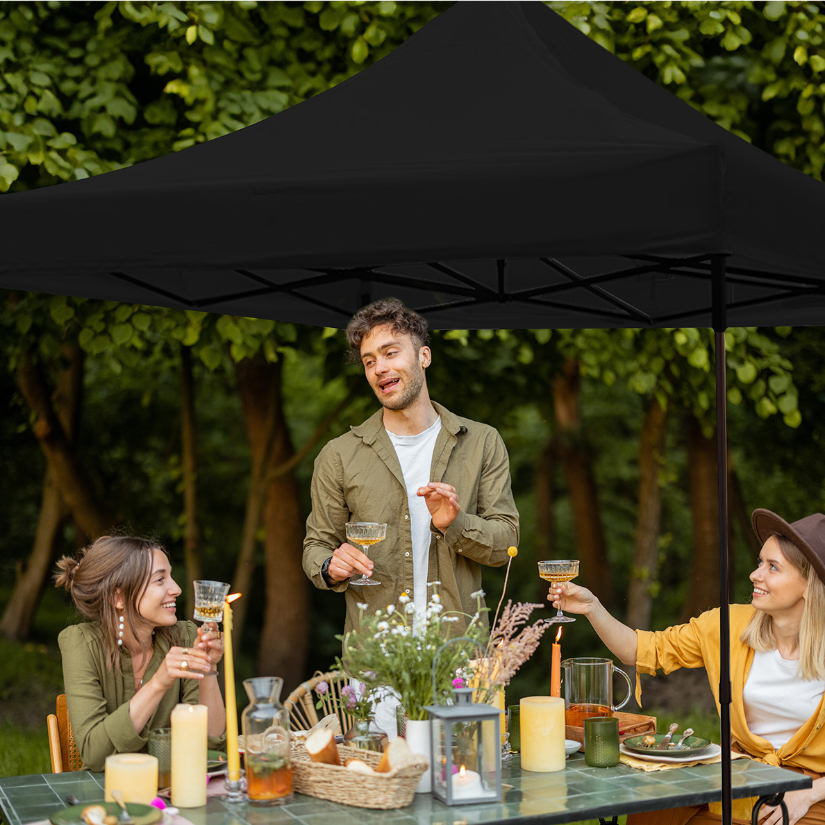 Group of people toasting drinks under a black canopy tent.
