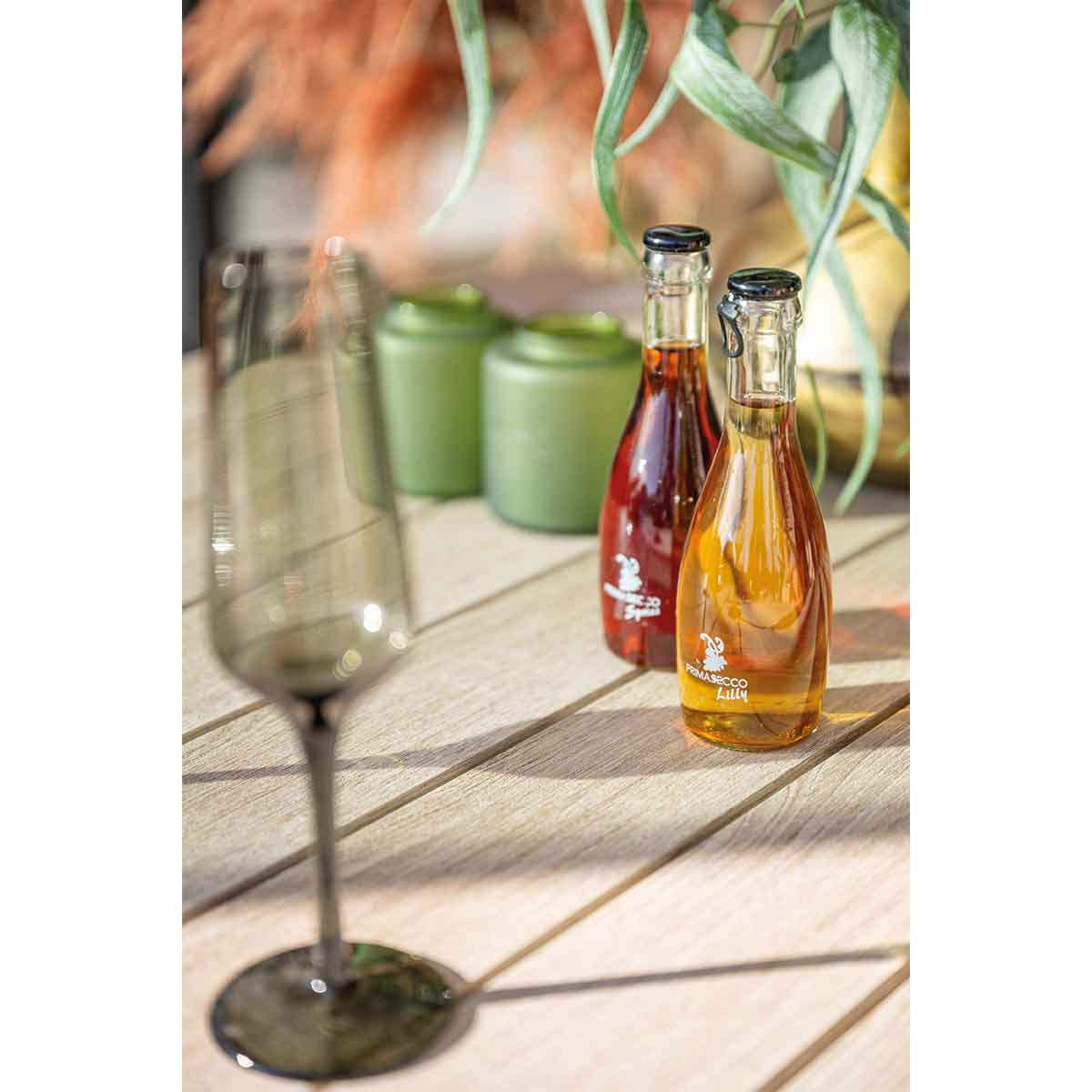 Bottles of drinks and a glass on a wooden table.
