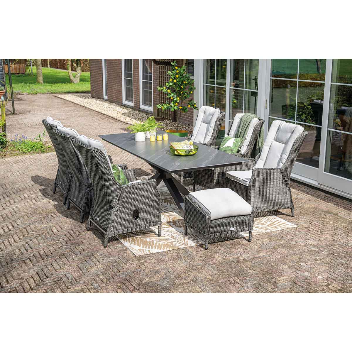 Patio set with table, chairs, and a footstool. Table has candles, and cushions are on the chairs.