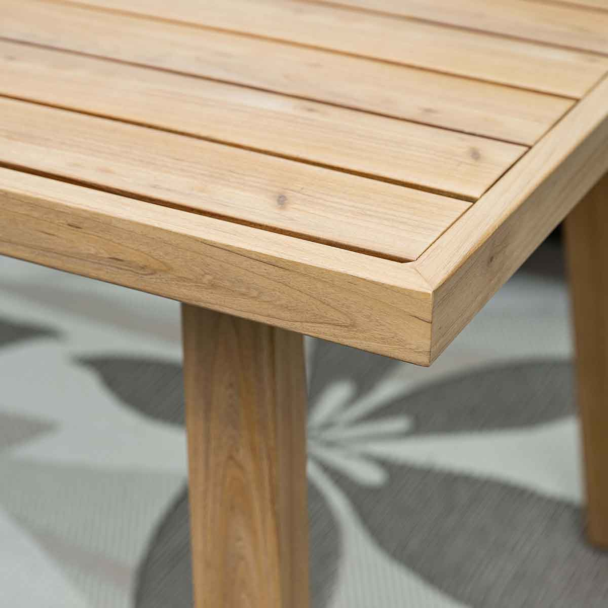 Close-up van een hoek van een lichte houten tafel. De tafel heeft een strak, eenvoudig ontwerp.