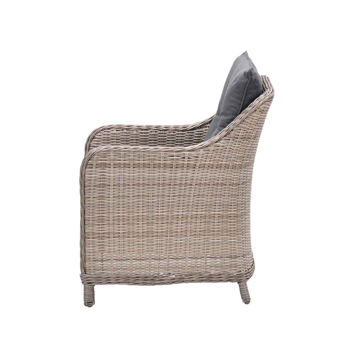 Zijaanzicht van een rotan stoel met een grijs kussen, witte achtergrond. Stoel van geweven materiaal.