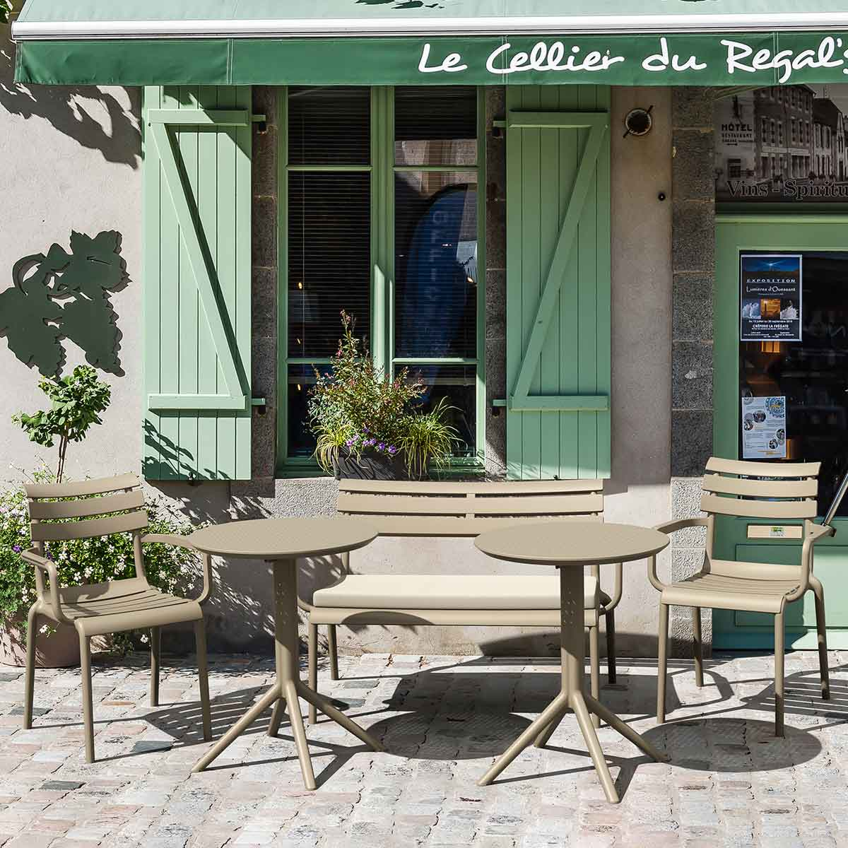 Café exterieur met tafels, stoelen en een groen luifel met Le Cellier du Regal's.