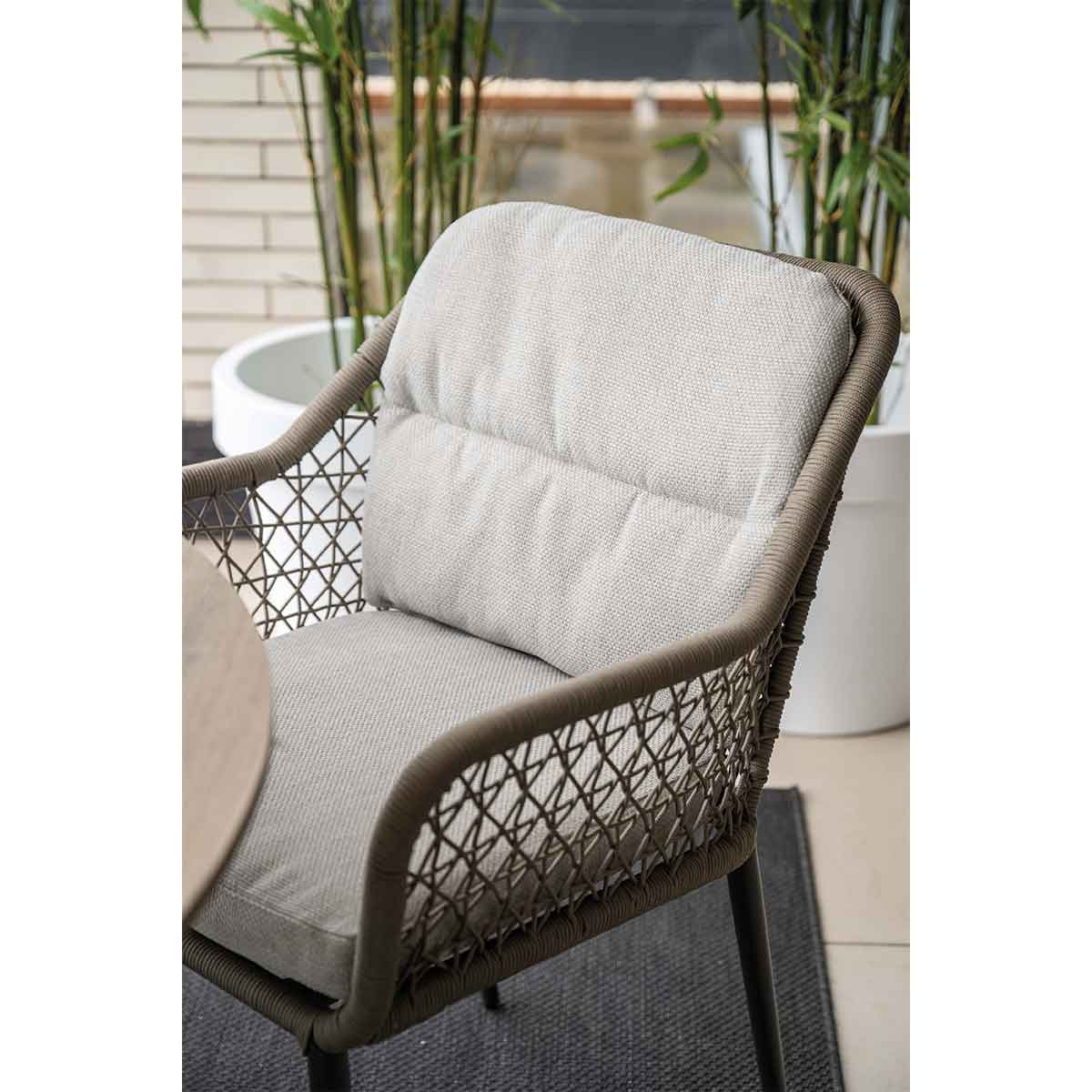 Close up of a chair. Woven back and armrests. Gray cushion.