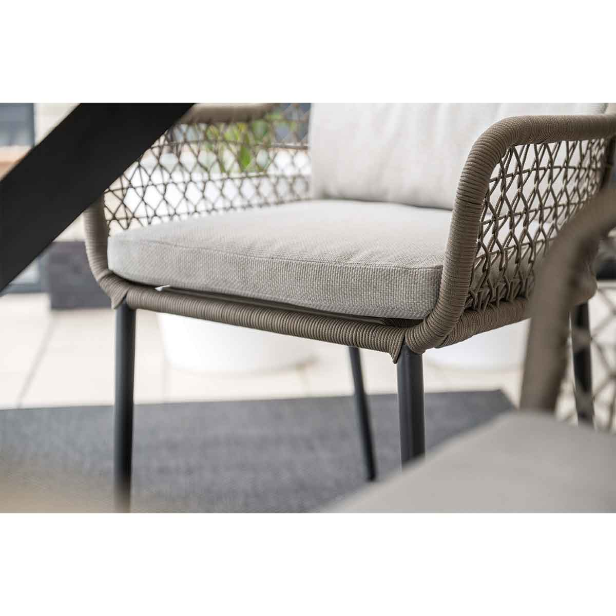 Close up of chair detail. Woven rope design. Grey cushion and black legs. Blurred background.