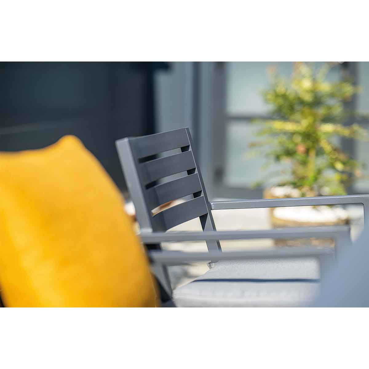 Back of a chair. Grey metal frame. Yellow cushion, dark background.