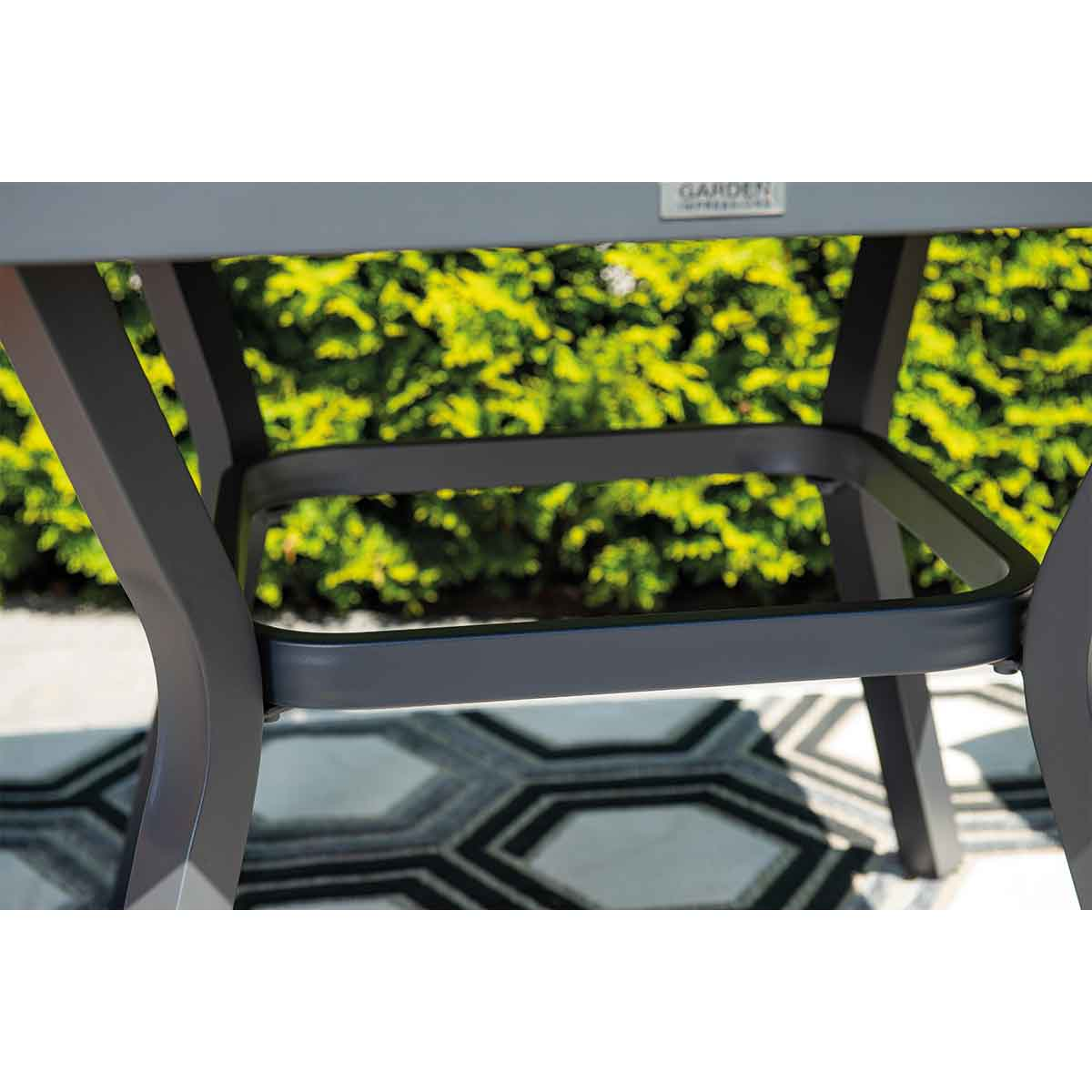 Close up of table base. Grey metal. Garden in the background.
