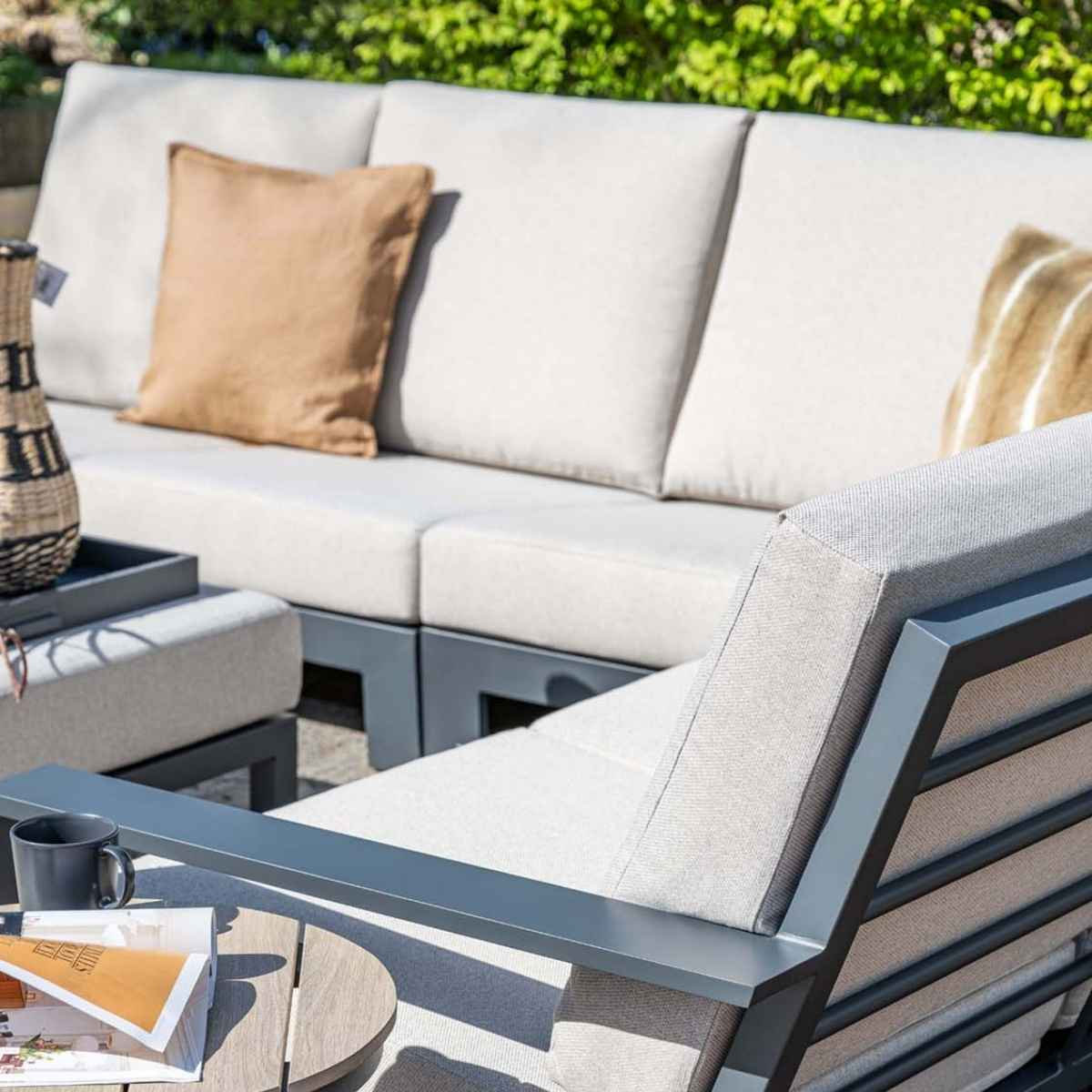 Close up of outdoor seating with cushions, pillows, and a table on a patio.