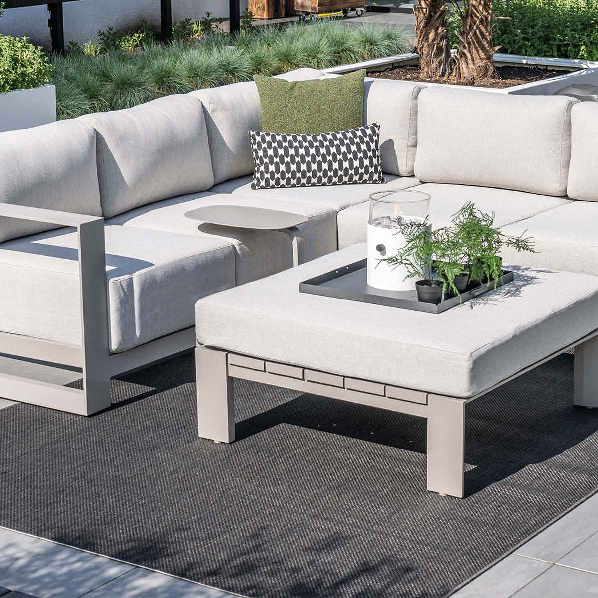 Coin salon extérieur avec canapé sectionnel, table basse et tapis.