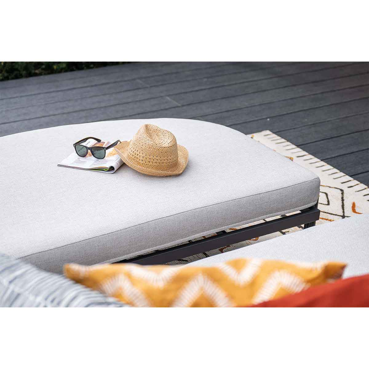 A sunbed with a hat, sunglasses, and a magazine. A yellow pillow is in the foreground.