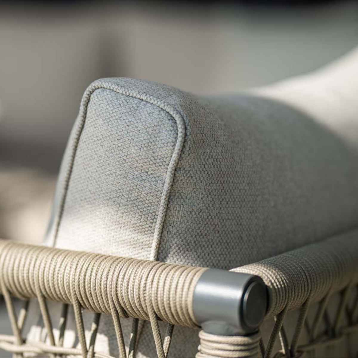 Gros plan sur un coin de coussin beige sur une chaise tissée. Arrière-plan flou.