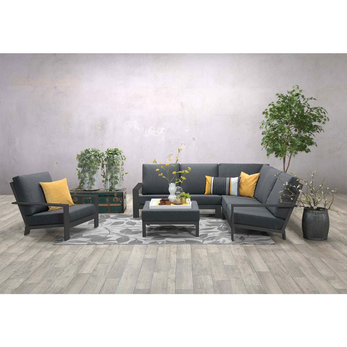 Outdoor sectional with cushions, small table and chairs on a wooden floor.