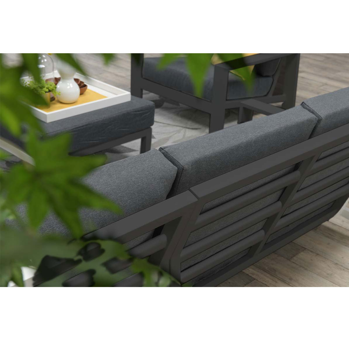 Outdoor seating area with a gray sofa, tray, and leaves in focus.