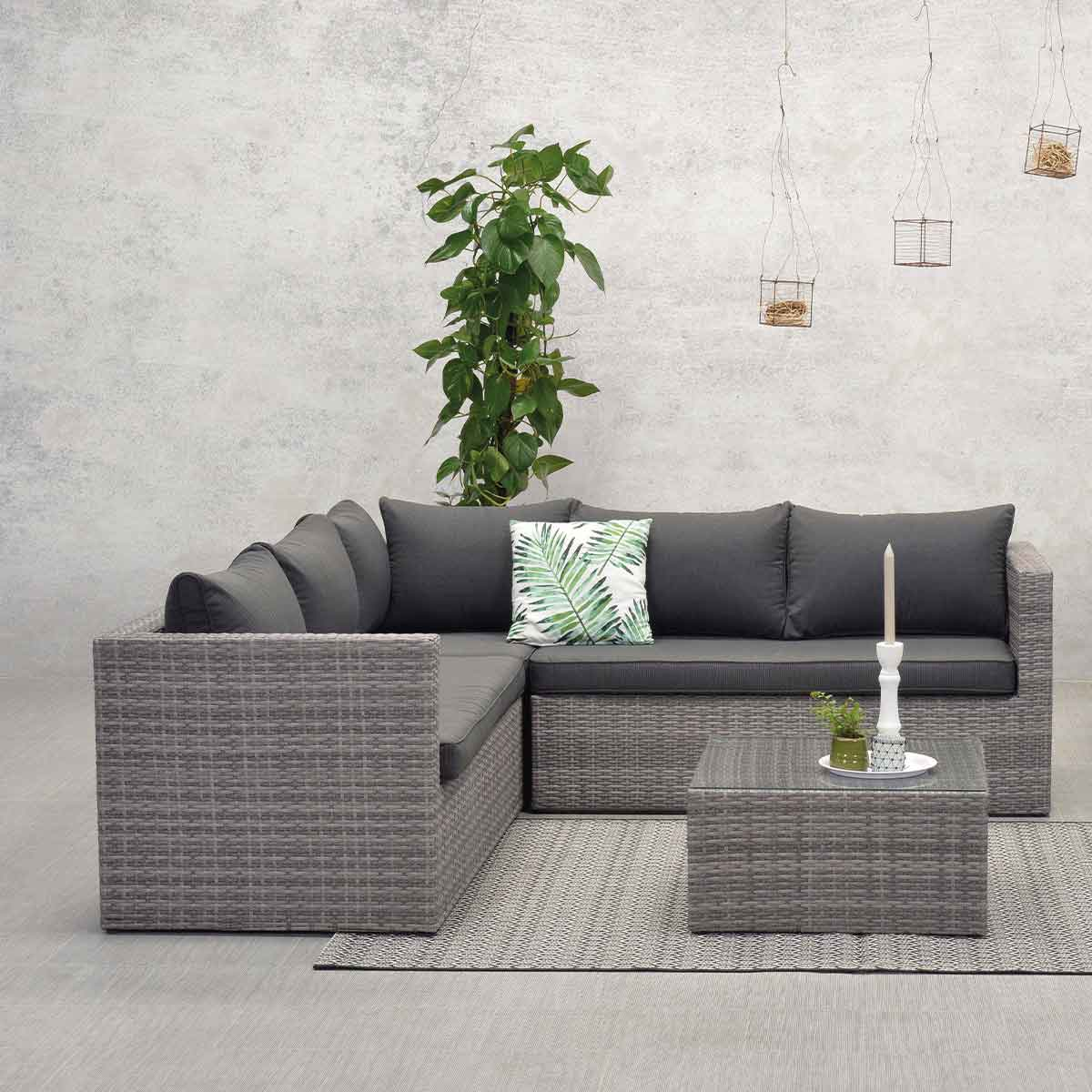 A gray outdoor sofa with cushions and a coffee table with a plant.