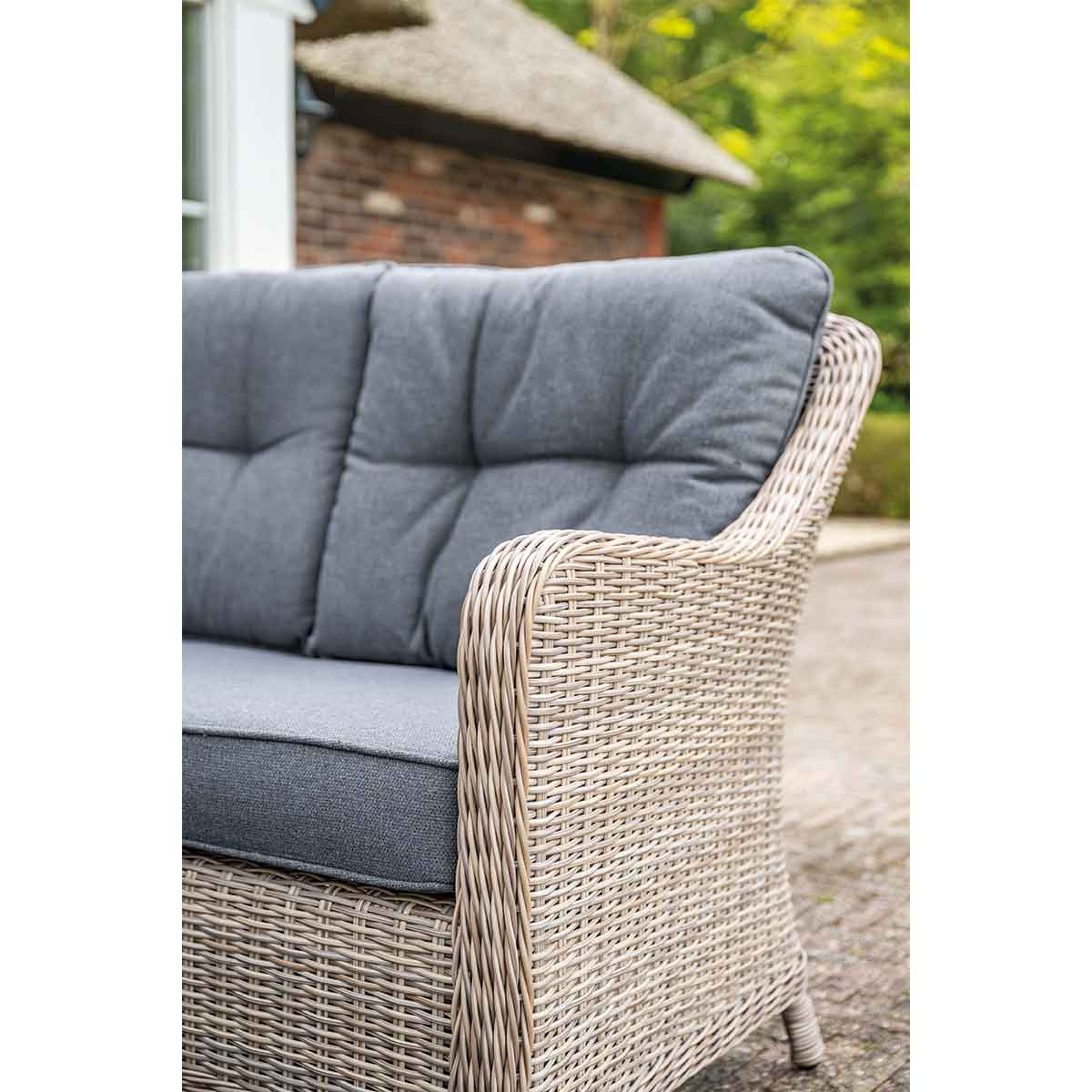 Close-up of outdoor sofa with gray cushions and a woven wicker armrest.