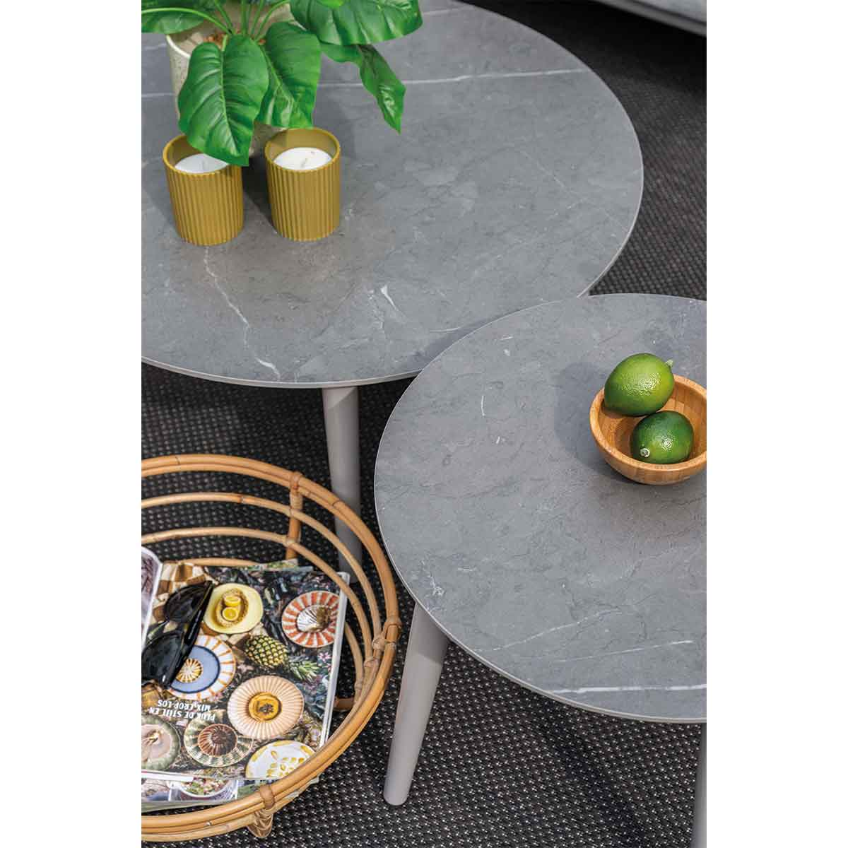 Two gray tables with objects on top. A basket with a magazine sits beneath one table.