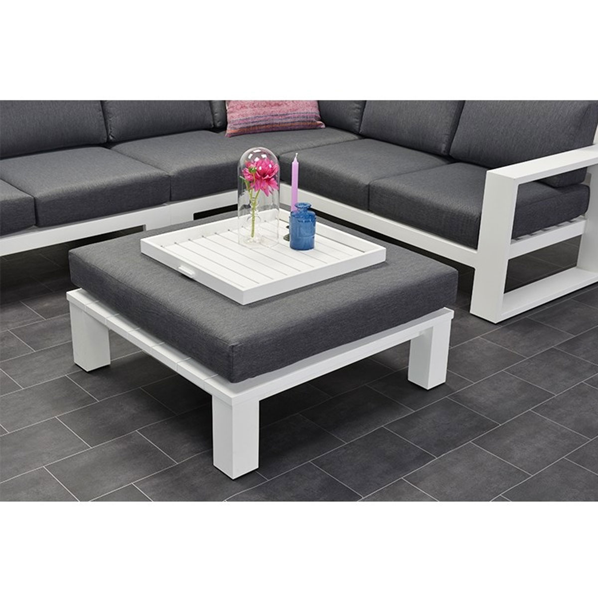 White square ottoman with tray and decor on a gray tiled floor.