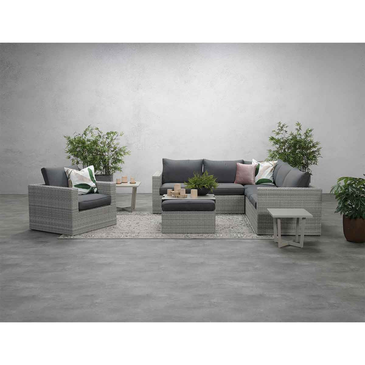 Outdoor seating set: gray furniture, plants, and a light gray rug.