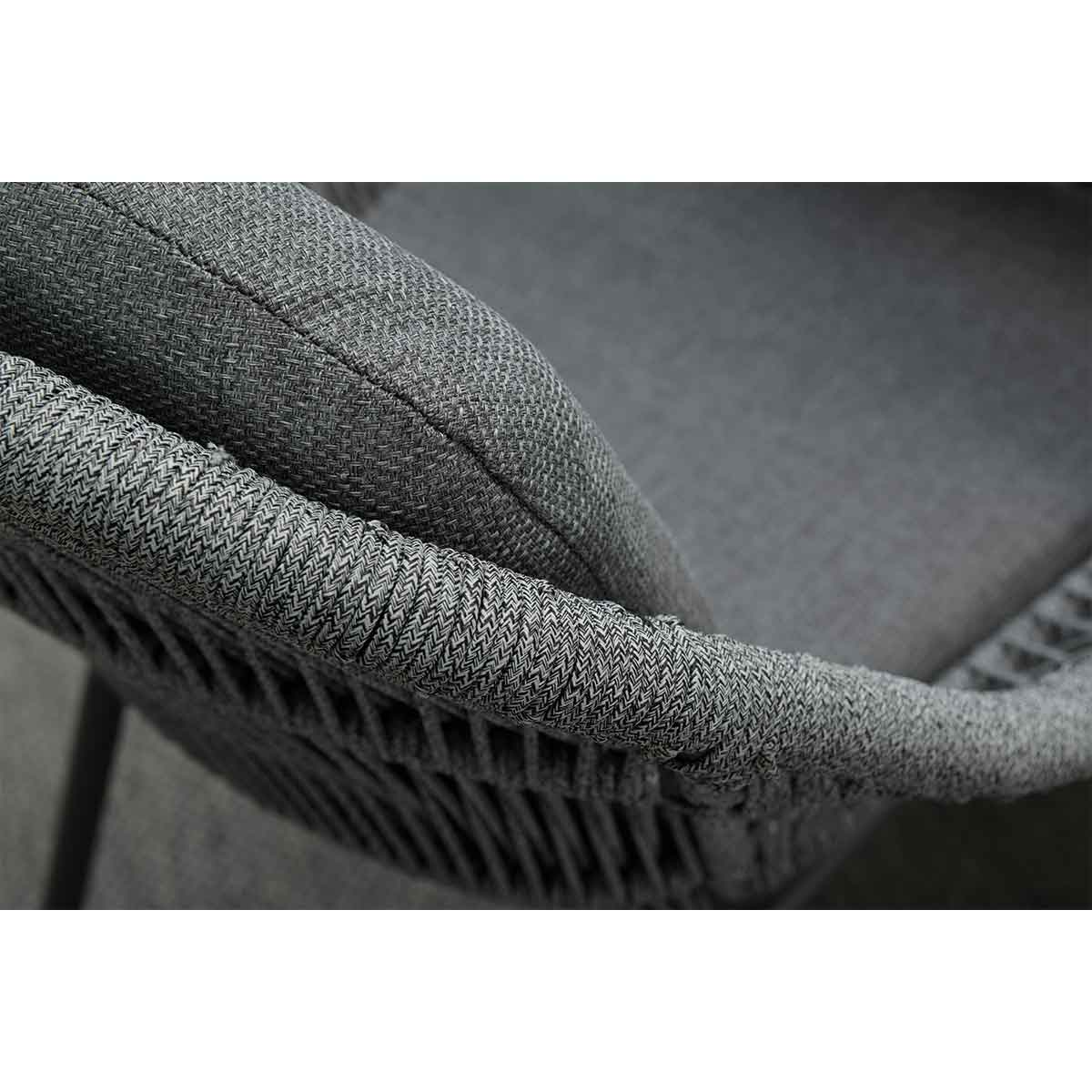 Close-up of a gray chair with woven texture. The chair has a curved back and armrest.
