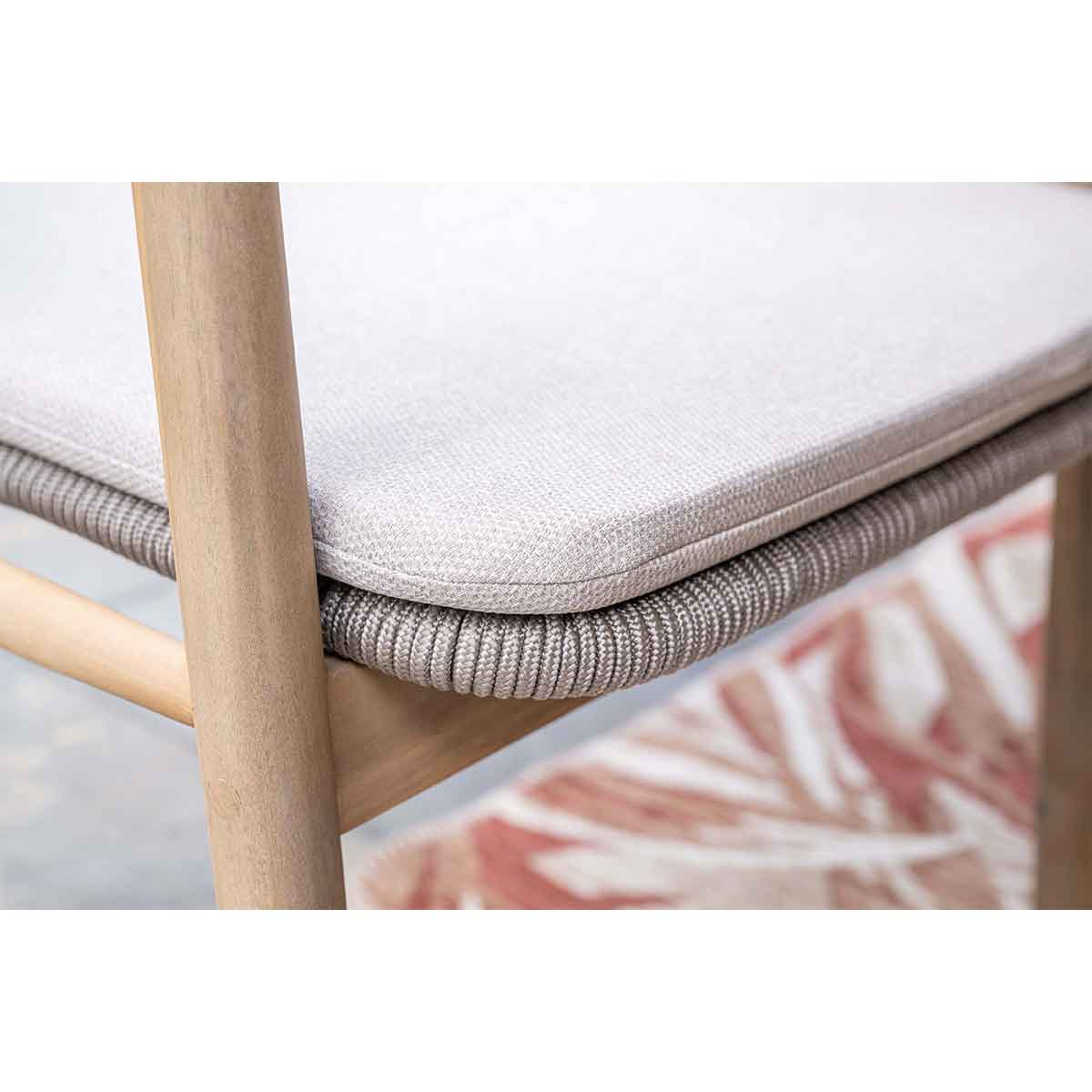 Close-up of the chair cushion and woven rope detail on the frame, with a patterned rug visible below.