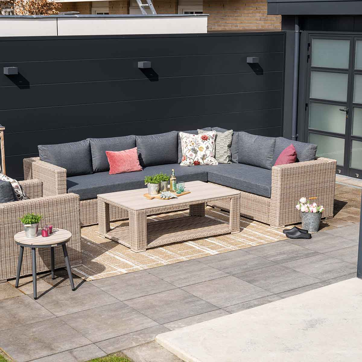Ensemble patio extérieur. Canapé sectionnel gris, table d'appoint, tapis et accessoires. Patio pavé.