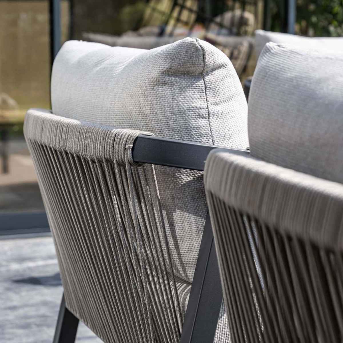 Close-up of outdoor armchairs, showing a rope design on the backrests. White background.
