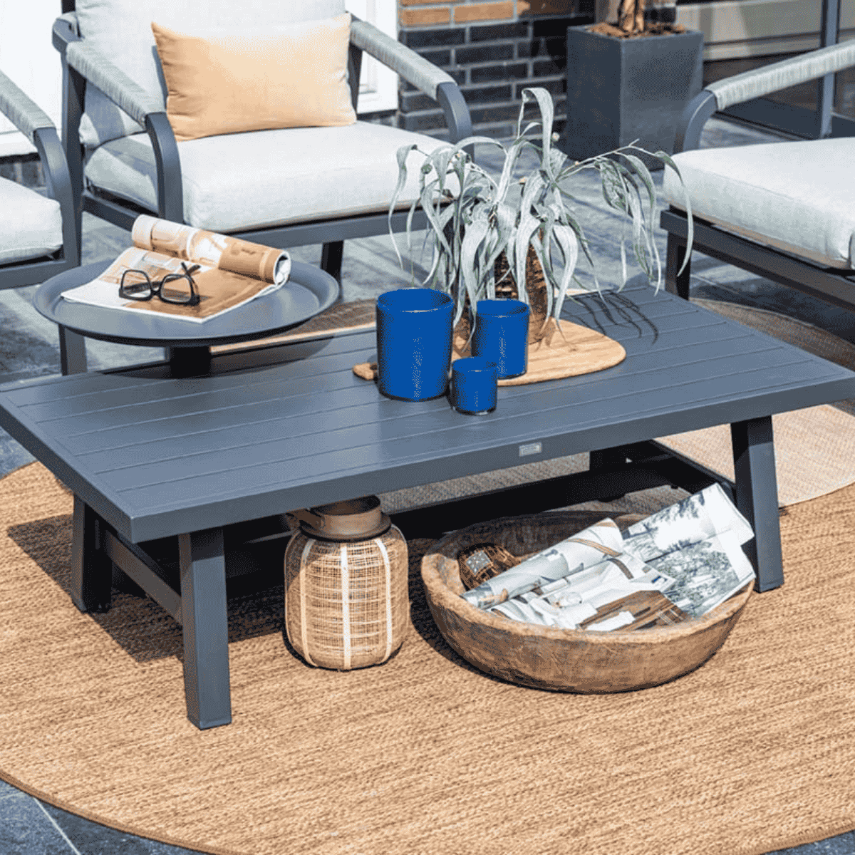 Outdoor table with magazines, decor, and blue vases. Located on a rug.