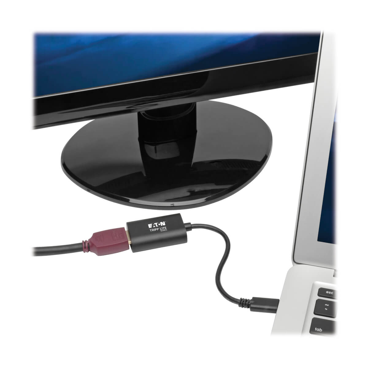 Ordenador portátil conectado a un monitor a través de un adaptador negro.