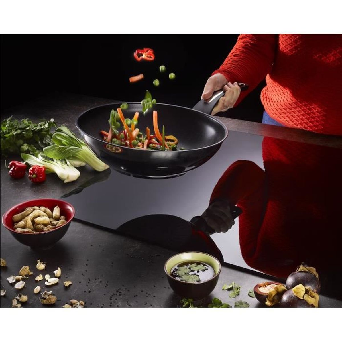 Wok z warzywami w ruchu, orzeszkami ziemnymi, mangostanem i czerwoną miską.