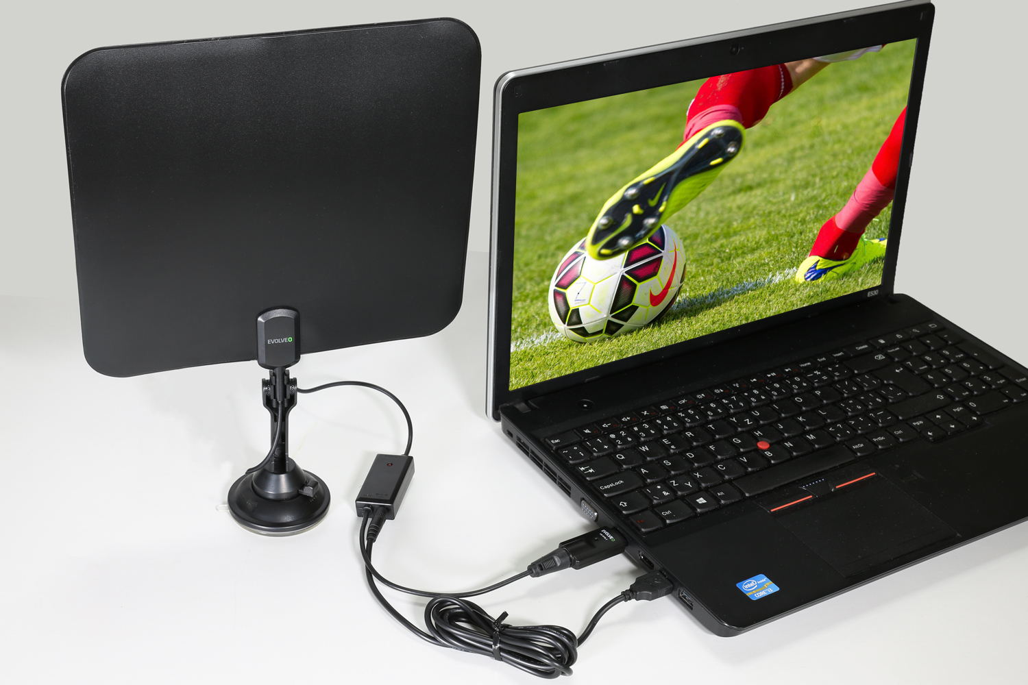 Laptop jest podłączony do anteny. Ekran wyświetla mecz piłki nożnej.