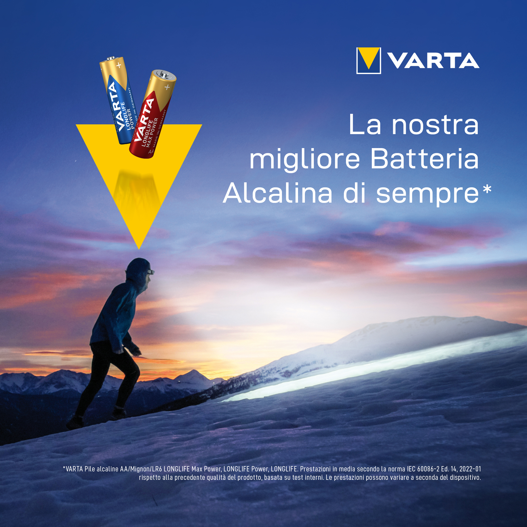 A person walks up a snowy mountain with two batteries. VARTA logo is in the top right corner.