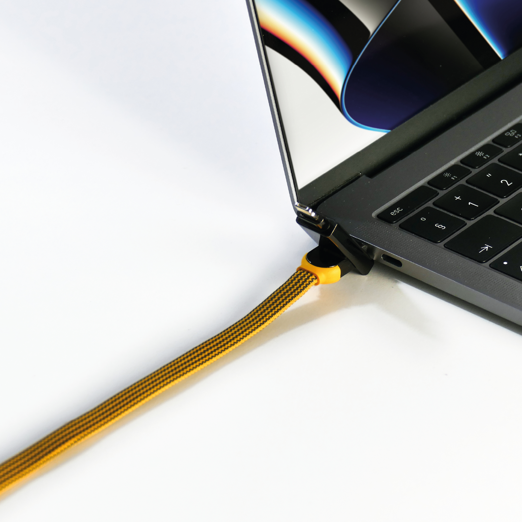 Ein Laptop mit einem gelb-schwarzen USB-C-Kabel, das eingesteckt ist, auf weißem Grund.