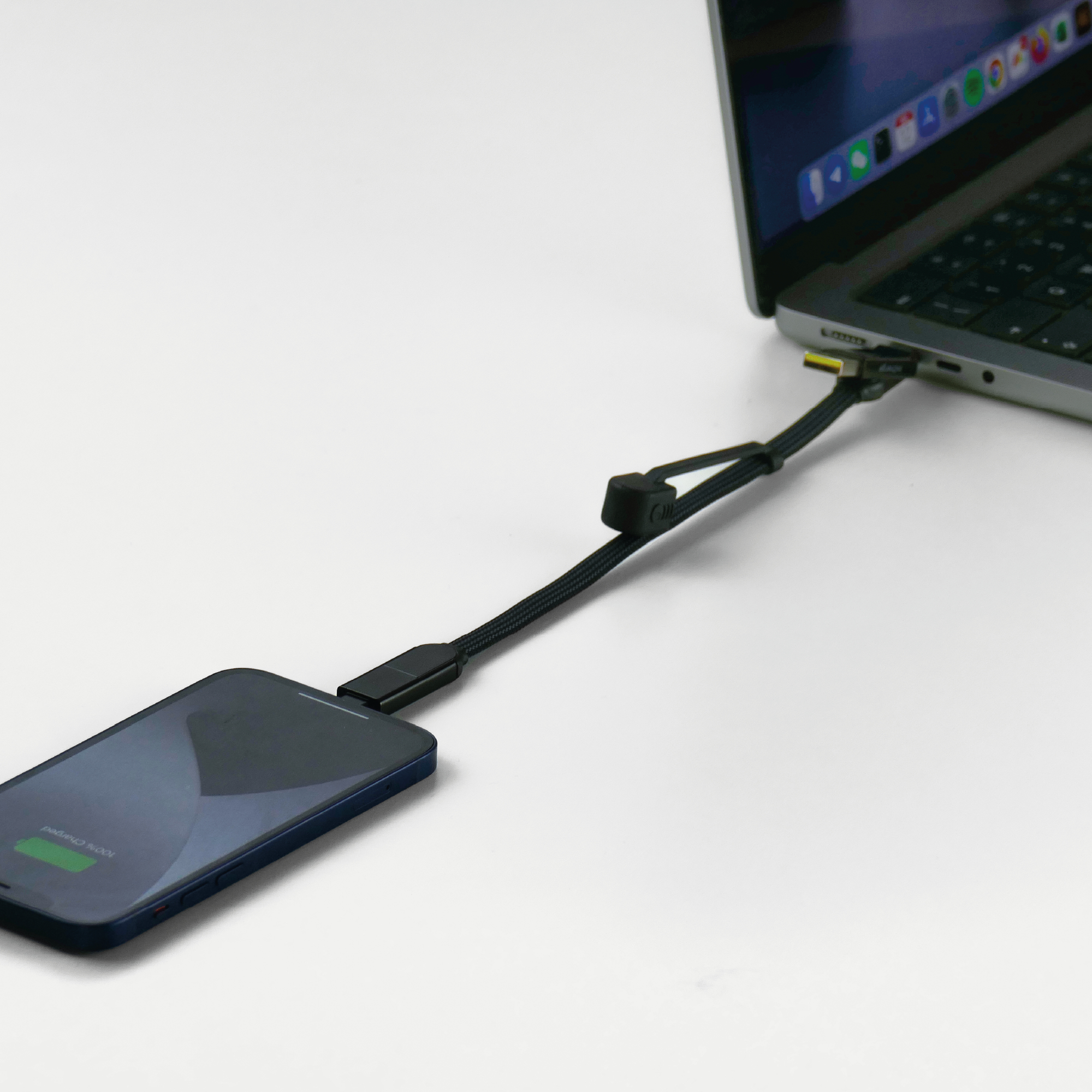 Schwarzes Ladekabel verbindet Telefon mit Laptop. Telefon zeigt 100% Ladung an.