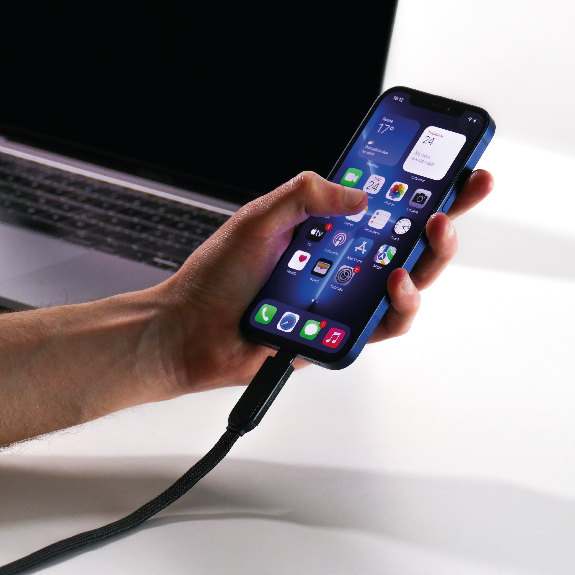 Personne tenant un téléphone connecté à un câble USB noir. L'écran du téléphone affiche une interface.