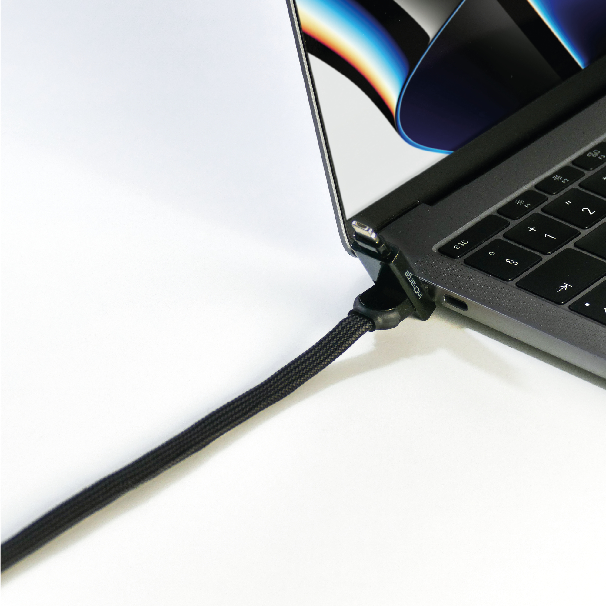 Schwarz geflochtenes Ladekabel, das mit einem Laptop verbunden ist. Weißer Hintergrund.