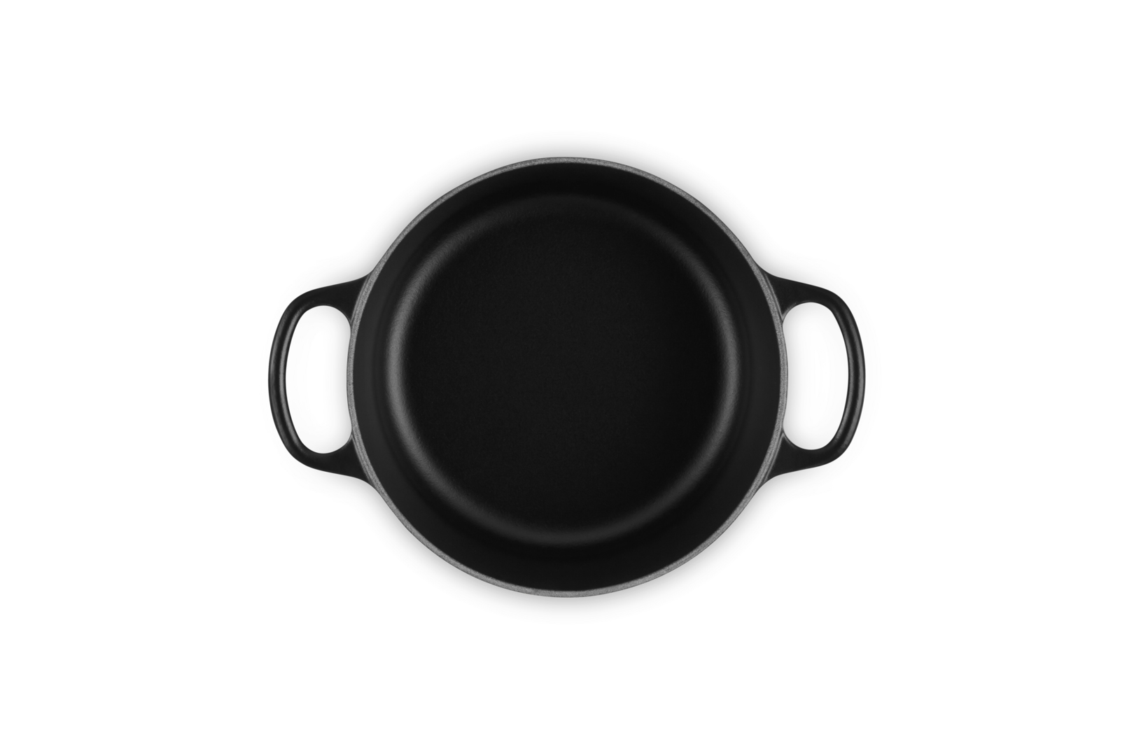 Black Le Creuset pot, top view. Handles are visible on a white background.