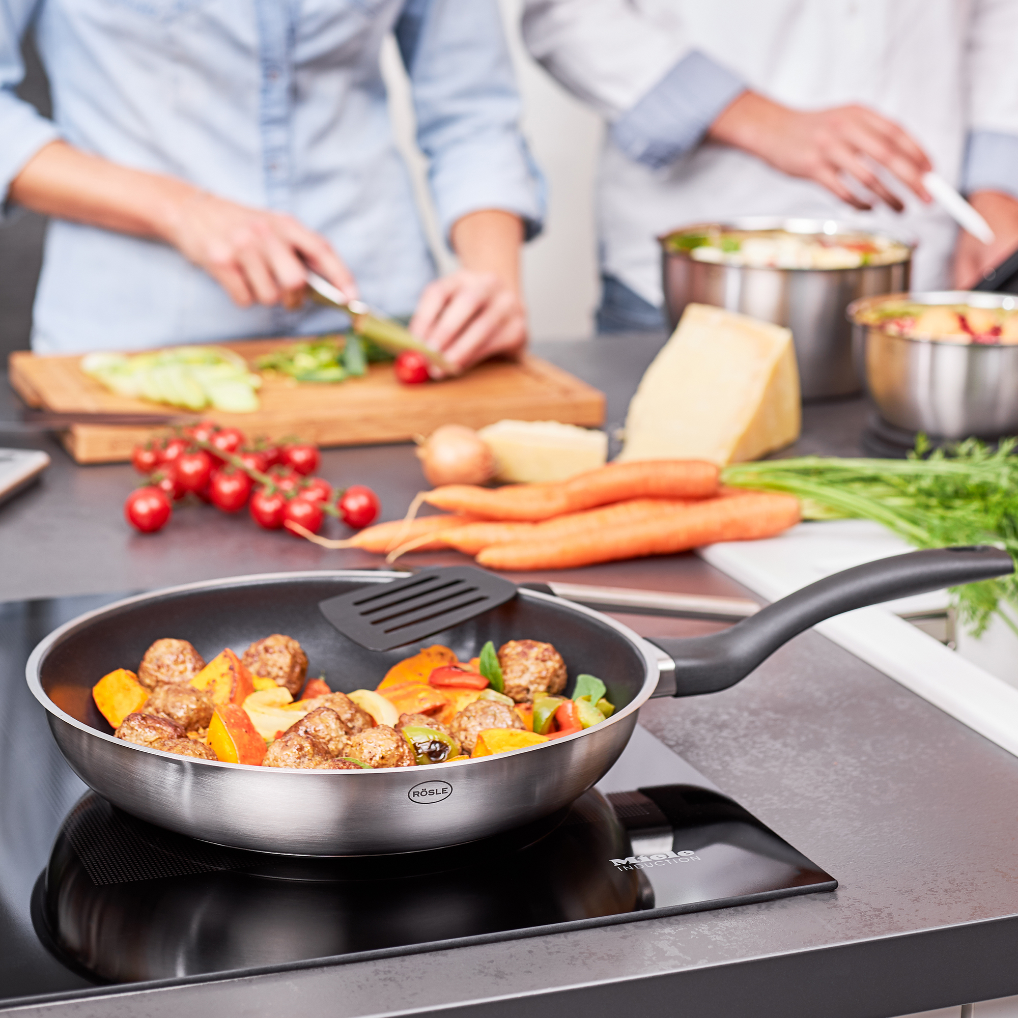 Kochszene. Pfanne mit Gemüse und Fleisch, zwei Personen kochen.