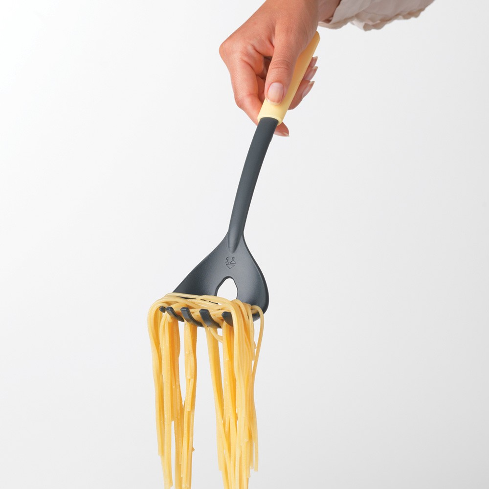Eine Person hält eine Spaghetti-Gabel, an der Spaghettistränge herunterhängen.